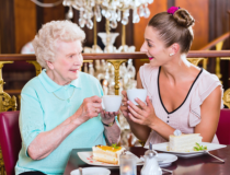 An old woman and caregiver drinking coffee